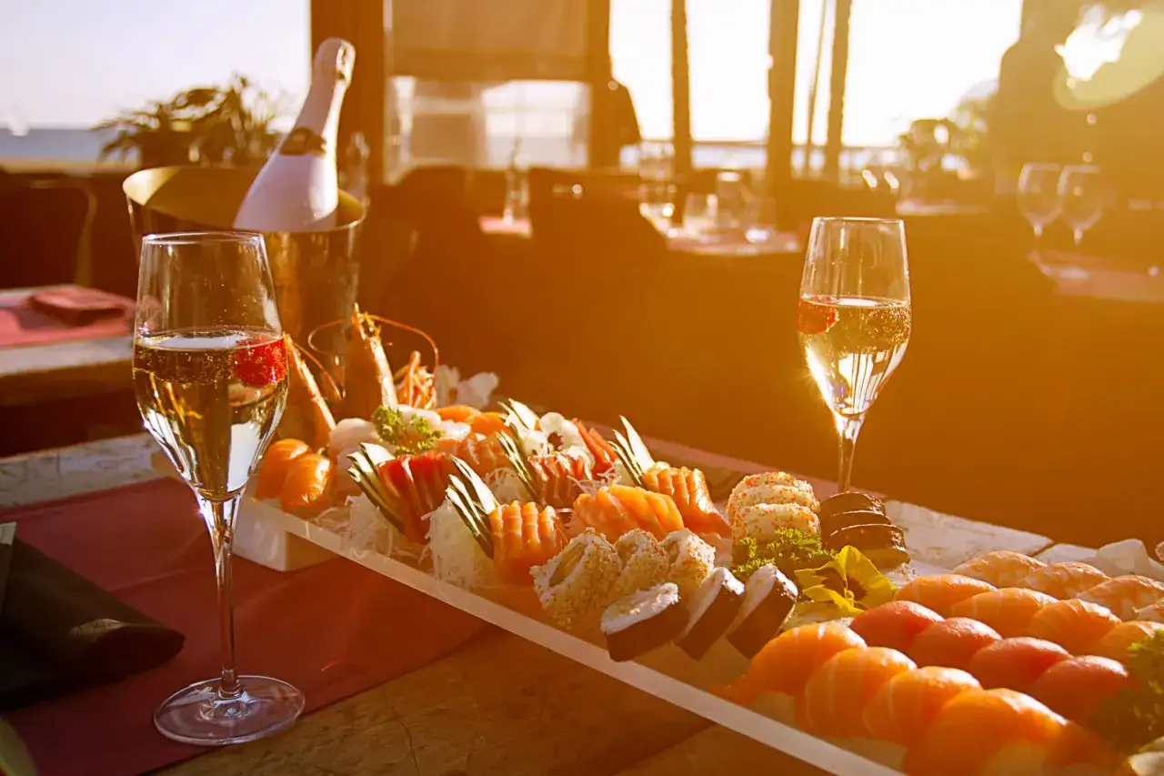 Un bicchiere di vino per sushi, con un vassoio di sushi e champagne, al tramonto.