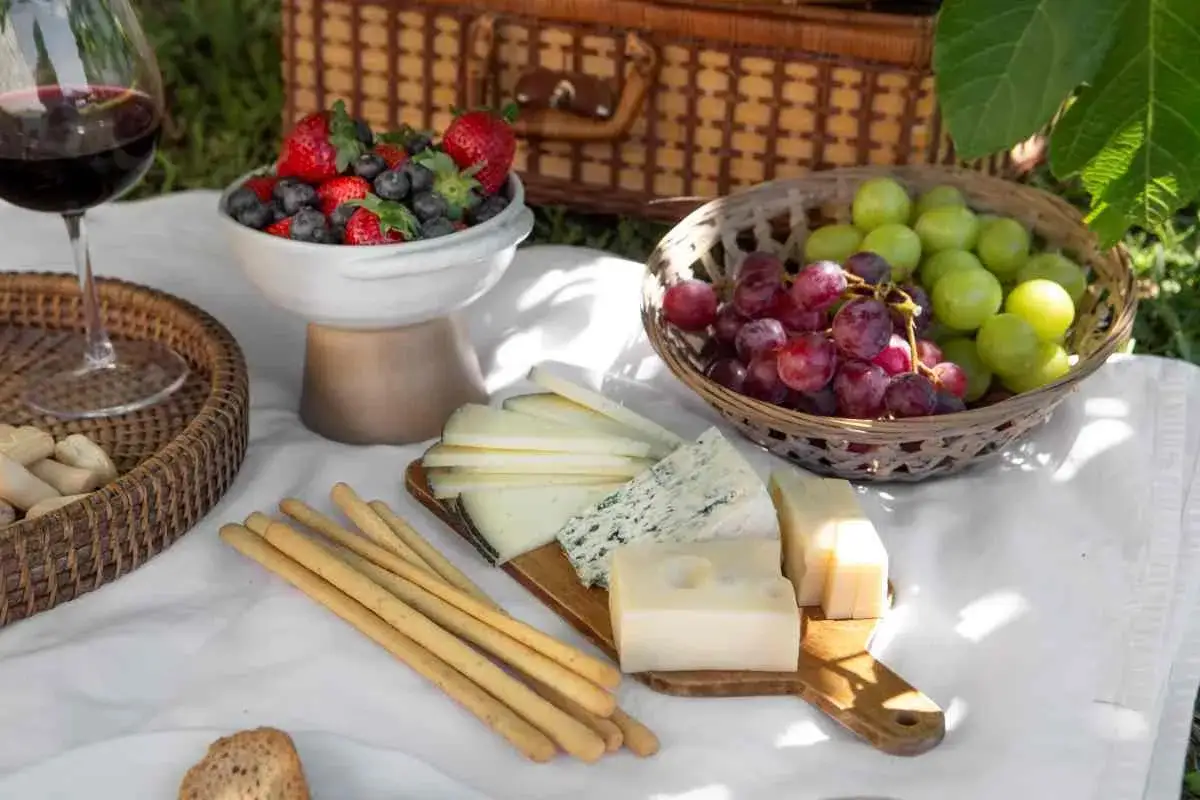 Un picnic con vino e formaggio, frutta fresca e grissini.