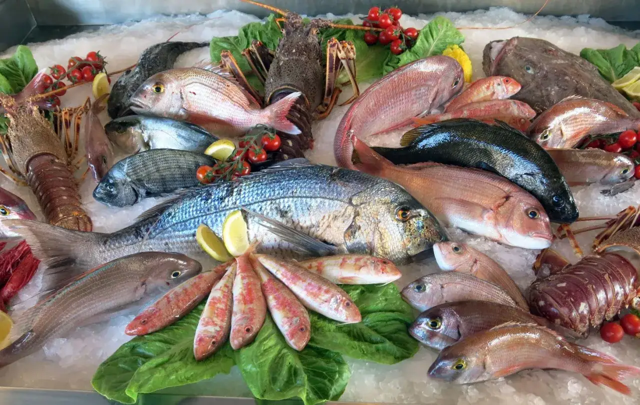 Un banco di pesce fresco su ghiaccio: aragoste, orate, triglie e un magnifico pesce azzurro.