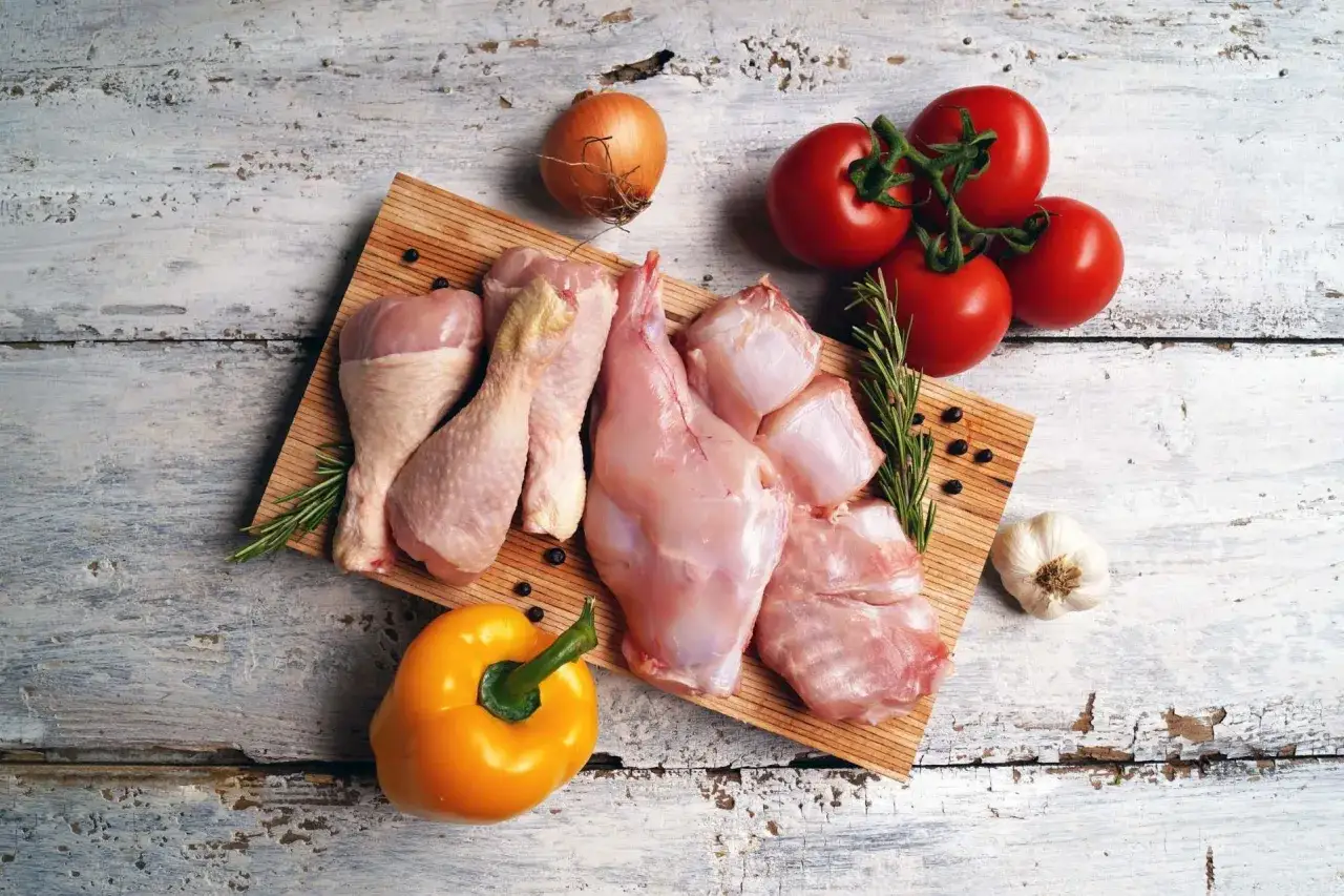 Tagli di coniglio e pollo, esempi di carni bianche quali sono, con pomodori, cipolla, aglio, peperone e rosmarino.