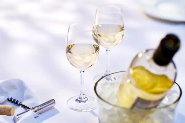 Due calici e una bottiglia di vino bianco in un secchiello di ghiaccio. Quanto tempo per il vino bianco in freezer? Meglio in frigo!