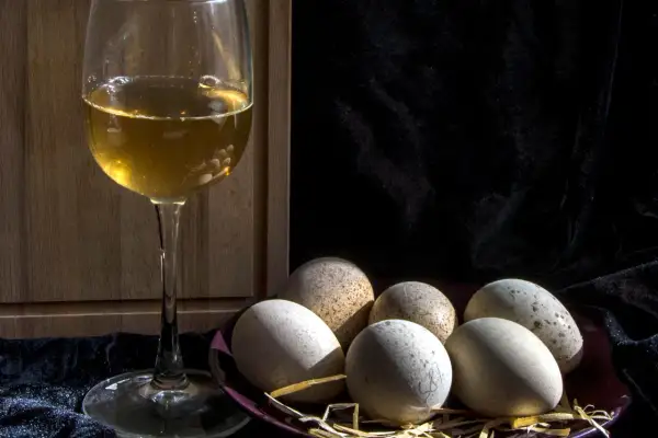 Un calice di vino dorato e un piatto di uova rustiche, un'idea su cosa abbinare alle uova per un pasto semplice e gustoso.