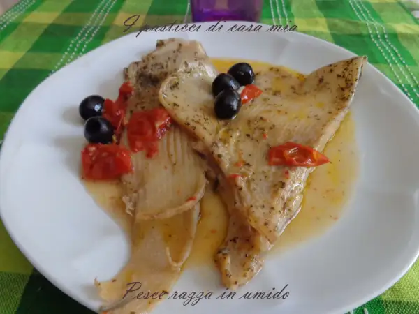 Piatto di pesce razza in umido con pomodorini e olive nere, condito con erbe aromatiche.