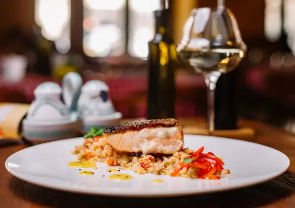 Salmone croccante su couscous con peperoni rossi. Un'idea perfetta su cosa abbinare al salmone, accompagnato da un bicchiere di vino bianco.