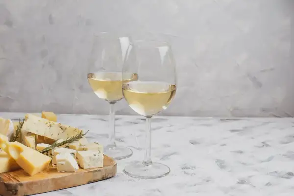Due calici di vino bianco, perfetti per accompagnare un tagliere di formaggi misti, tra cui erborinato e stagionato.