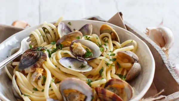 Un piatto invitante di spaghetti alle vongole, con pasta spessa e molluschi succulenti, guarnito con prezzemolo fresco.