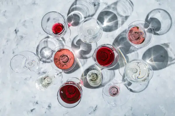 Vari calici di vino rosso, rosato e bianco, con ombre suggestive. La temperatura ideale per gustare un buon vino rosso è fondamentale.